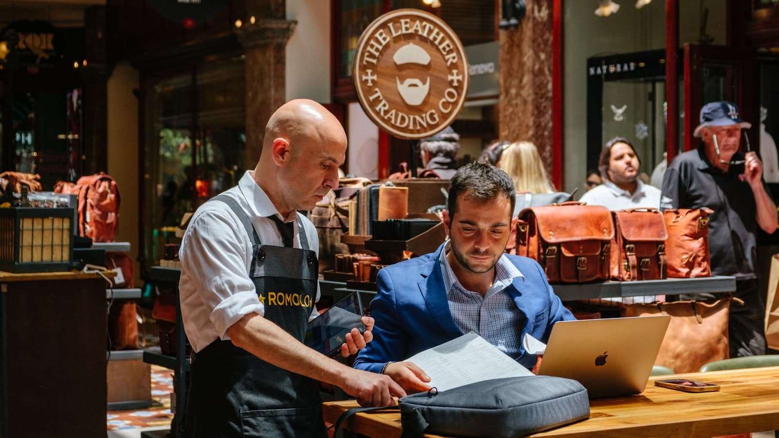 Zwei Gewerbetreibende prüfen Unterlagen zur Gewerbeanmeldung am Laptop in ihrem Geschäft
