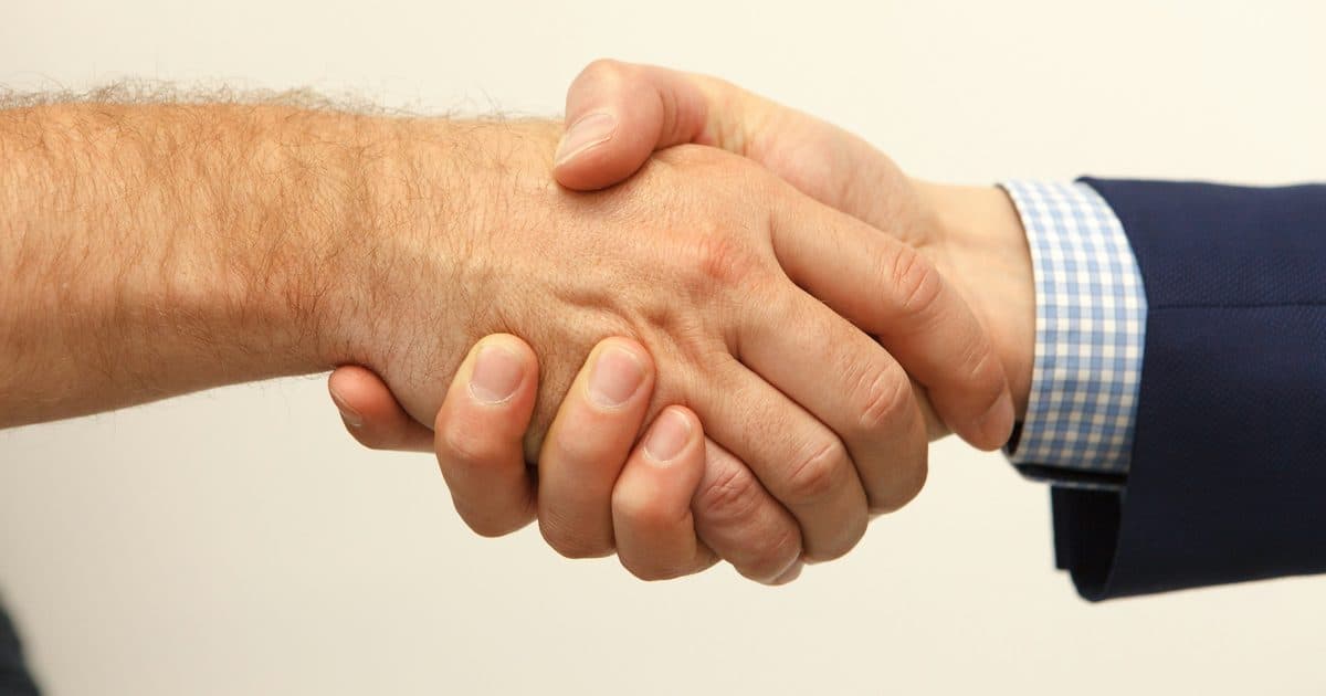 Zwei Hände beim Handschlag vor hellem Hintergrund, Symbolbild für die Gründung einer OG oder KG