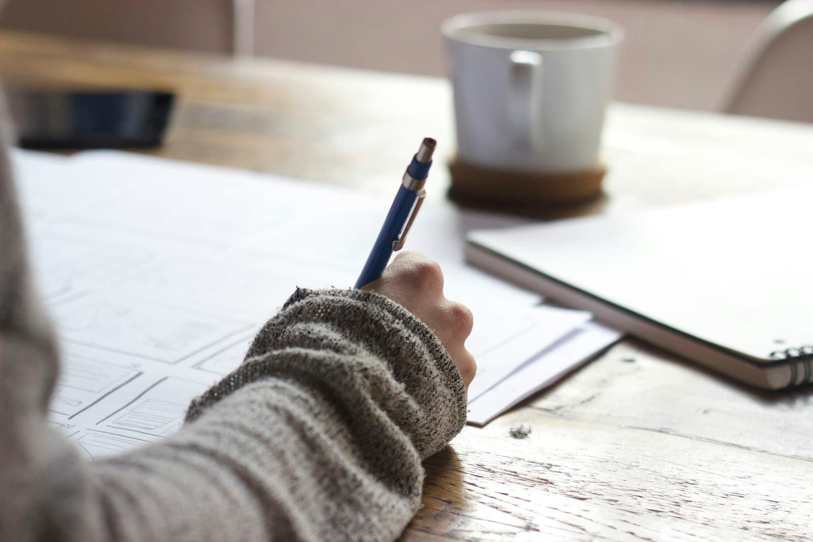 Person mit Laptop und Checkliste auf einem Schreibtisch, daneben Kaffeetasse und Notizen, symbolisiert die strukturierte Auswahl eines Virtual Office Anbieters