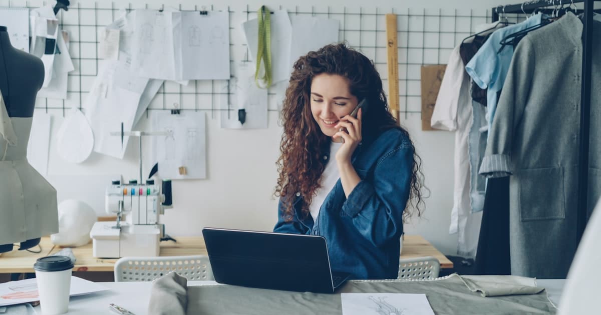 Selbstständige Modedesignerin arbeitet am Laptop in ihrem Atelier